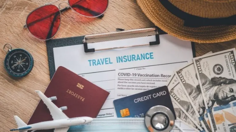 travel items scattered on a table, with travel insurance in the middle