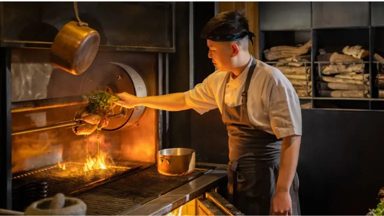 a chef at the grill in the kitchen of nixta restaurant