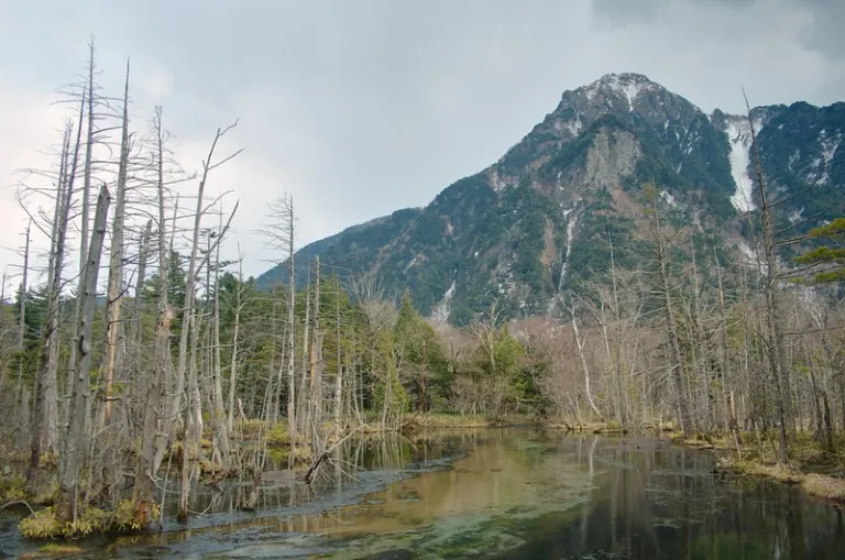 Mountain landscape reflected in calm water at Kamikōchi in the Japanese Alps during misty weather