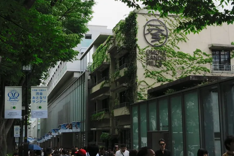 Exterior of Omotesando Hills in Tokyo, designed by Tadao Ando with ivy-covered walls and a minimalist fa&ccedil;ade.