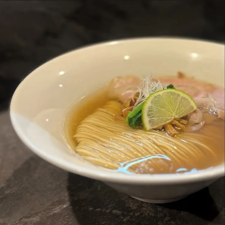 A bowl of clear broth shio ramen topped with lime, sliced pork, and handmade noodles at RAMEN MATSUI in Tokyo.