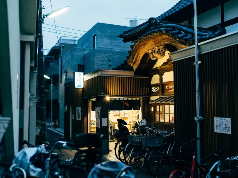 Exterior of Kosugiyu, a historic sento in Koenji, Tokyo, with bicycles parked outside at dusk.