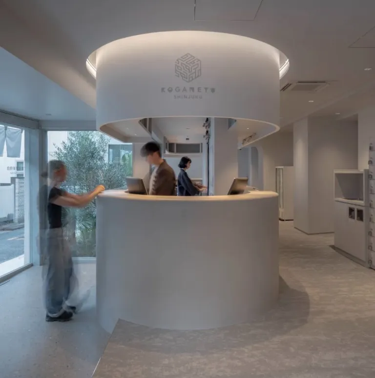 Modern white reception counter inside Koganeyu, with staff assisting visitors in a bright minimalist interior.