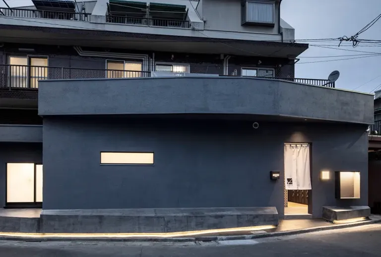 Exterior of Kairyou-yu in Shibuya, Tokyo, featuring a dark modern fa&ccedil;ade and a white noren curtain at the entrance.