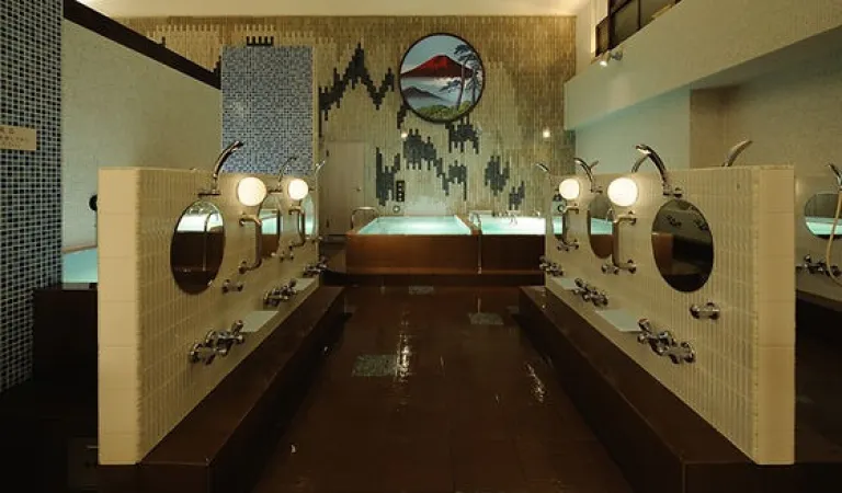 Bathing area inside Bunkayokusen, featuring tiled washing stations, round mirrors and a Mount Fuji mural above the bath.