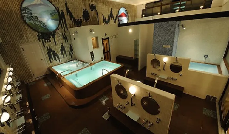 Spacious bathing area inside Bunkayokusen, featuring tiled baths, round mirrors and a modern Mount Fuji mural.