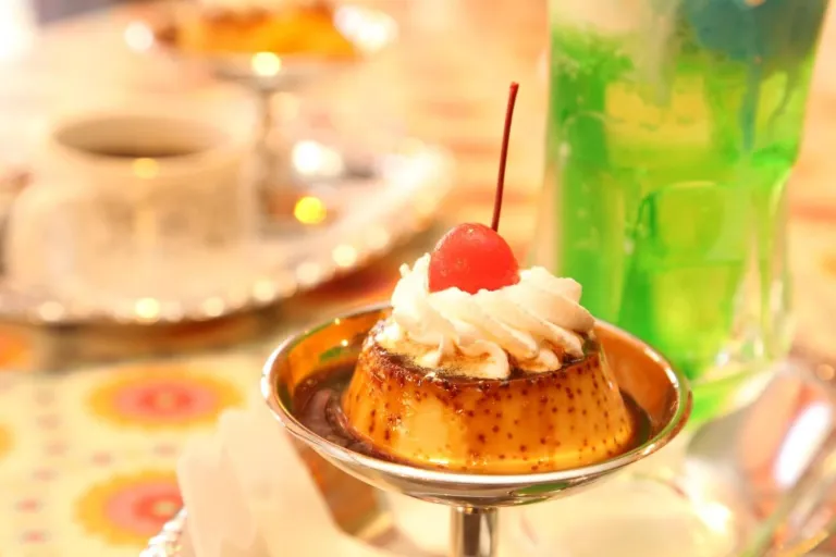 Handmade pudding topped with cream and a cherry, served with a green cream soda at Cafe Sepia in Shibamata.