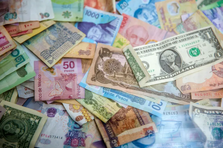 A collection of various international banknotes scattered across a flat surface