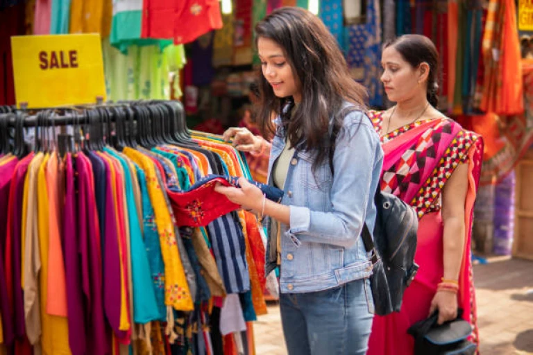 Mother and daughter shopping together for clothes at outdoor street market