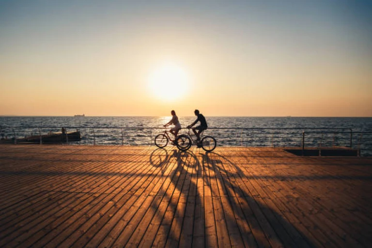 Travelers cycling together at the beach at sunrise sky